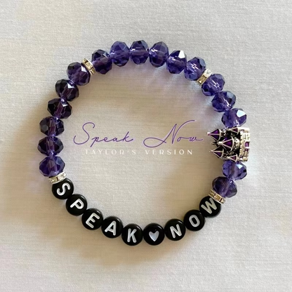 Purple beaded bracelet with 'Speak Now' black beads and a castle charm.