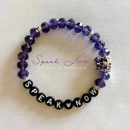 Purple beaded bracelet with 'Speak Now' black beads and a castle charm.