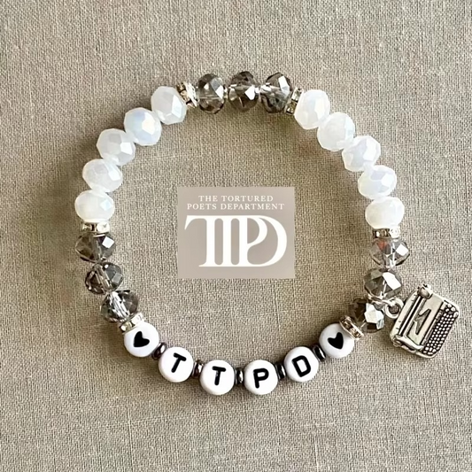 TTPD beaded bracelet with white and smoky crystal beads, heart accents, and a silver typewriter charm inspired by The Tortured Poets Department.