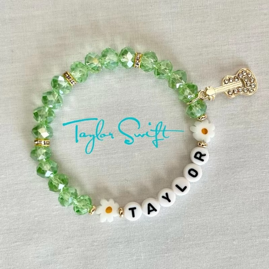 Green beaded bracelet with 'Taylor' and guitar charm.